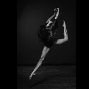A show dance performer captured mid‑air during a dynamic jump, demonstrating power, expression, and theatrical movement.